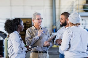 group of four motor carrier professionals huddled in a group talking 