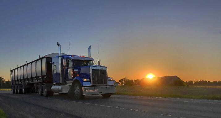 a truck driving on a road in front of a sunset 